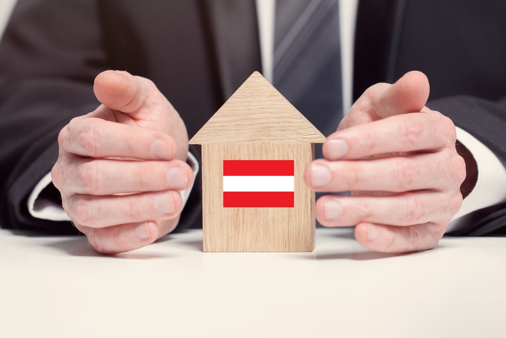Businessman,Hand,Holding,Wooden,Home,Model,With,Austrian,Flag.,Insurance immobilien in österreich