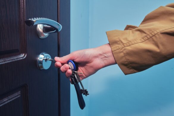 Hand,Inserting,Key,Into,Door,Lock.,Close-up,Shot,Of,Hand